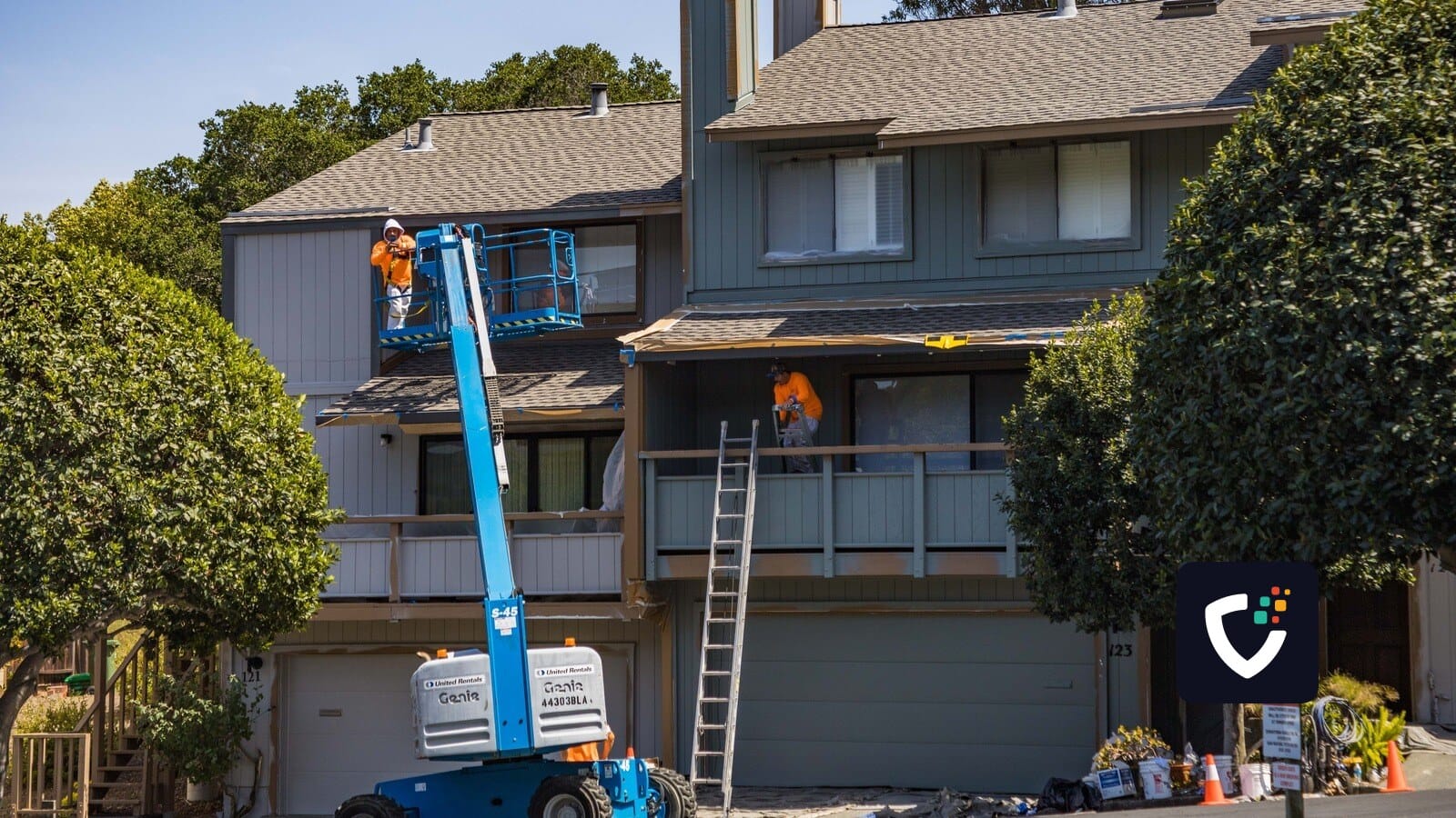 House being renovated with workers on a hydraulic lift in an urban area