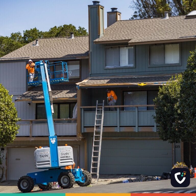 House being renovated with workers on a hydraulic lift in an urban area