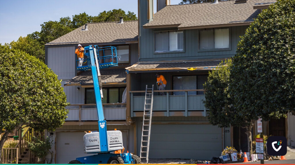 House being renovated with workers on a hydraulic lift in an urban area