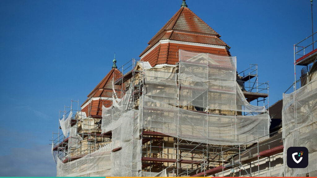 A historic building under restoration, covered in scaffolding and protective nets