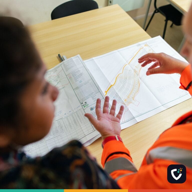 Two engineers reviewing construction blueprints on a table in an office setting