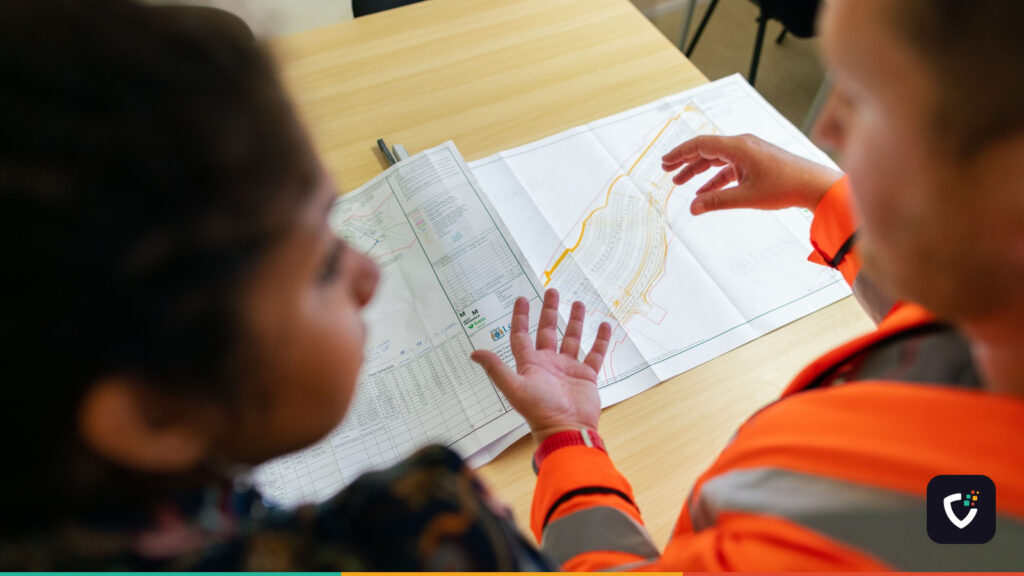 Two engineers reviewing construction blueprints on a table in an office setting