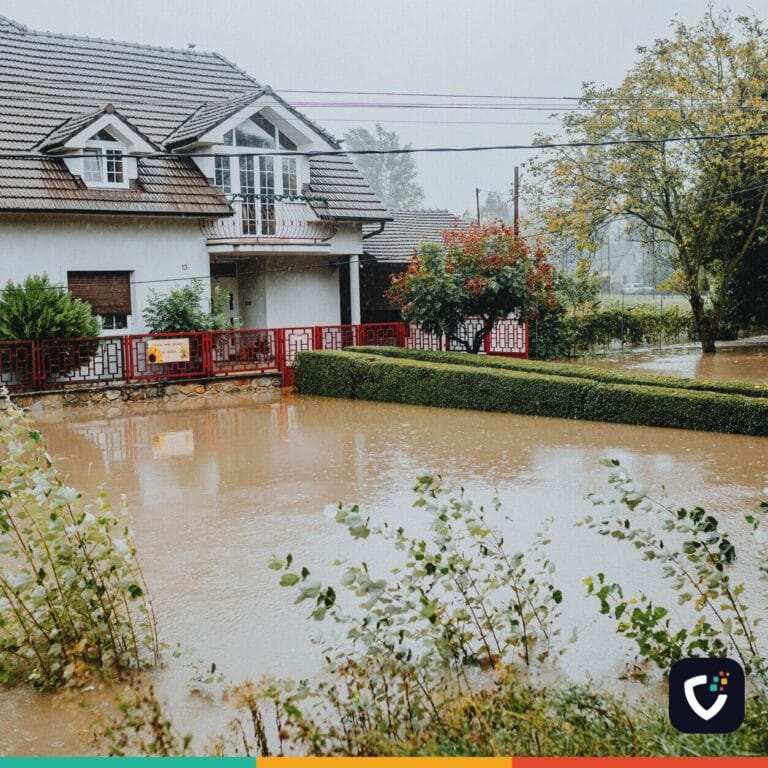 A suburban house surrounded by floodwaters after heavy rain, showing impact of natural disaster