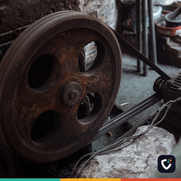 Close-up of a rusted industrial machine wheel in an old workshop setting