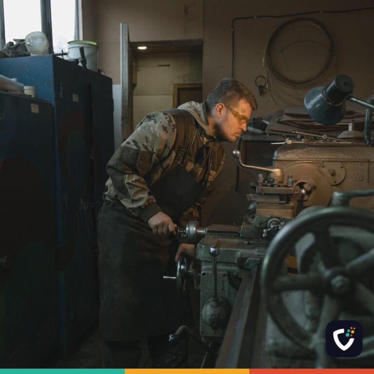 Caucasian man operating a lathe in an industrial workshop setting, focused on precision work