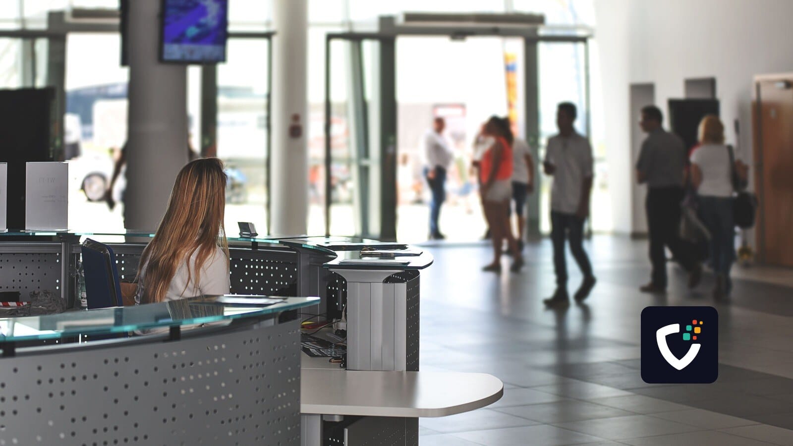 A bustling office reception area with people walking and a receptionist at a modern desk