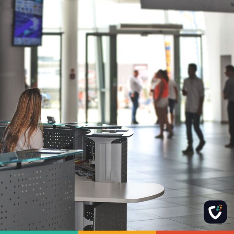 A bustling office reception area with people walking and a receptionist at a modern desk