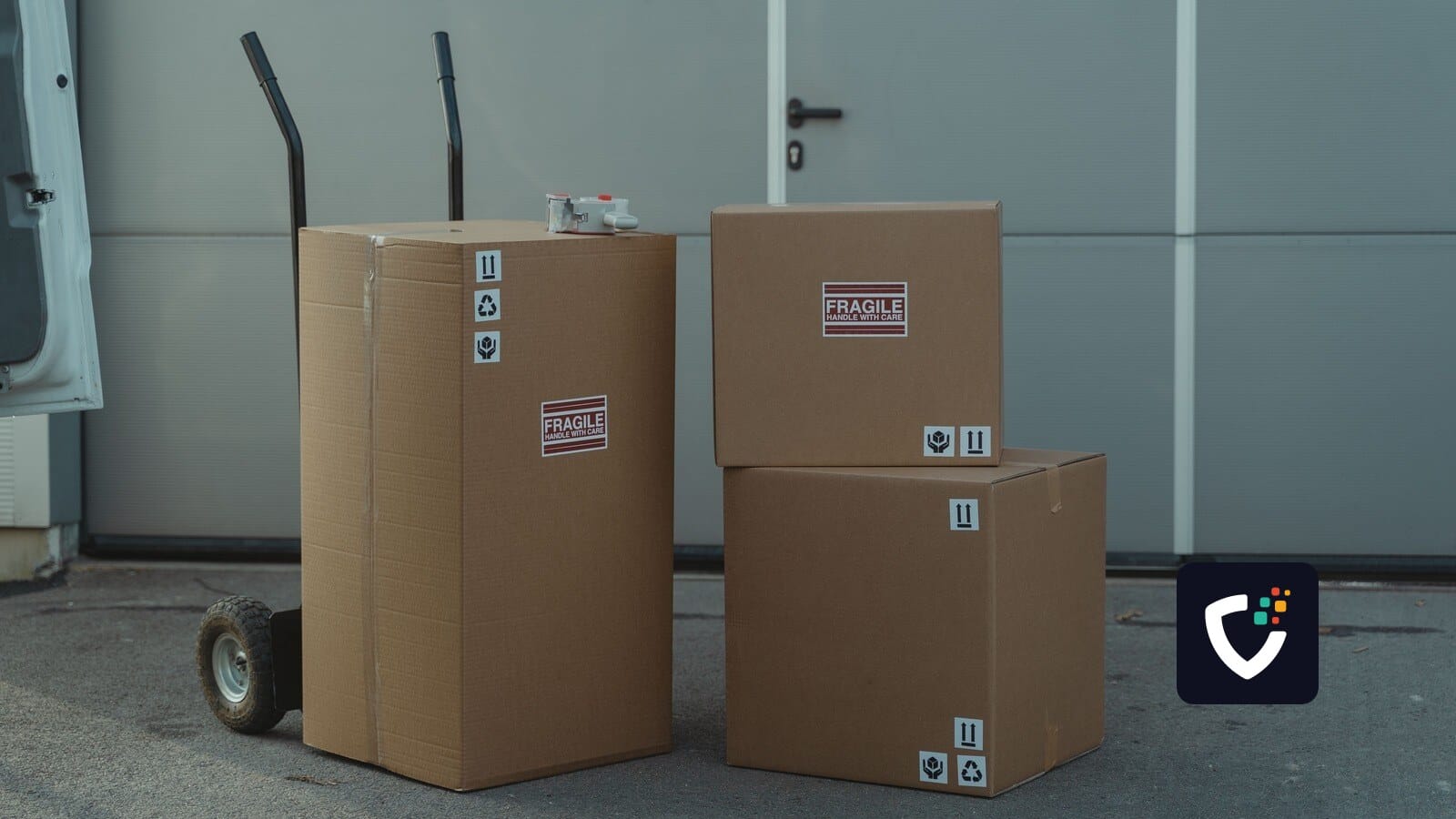 Three cardboard boxes on a dolly, ready for shipping outside a warehouse