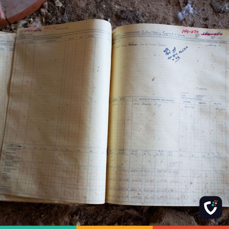 An old ledger lying open on a dusty floor, its columns filled in by hand.
