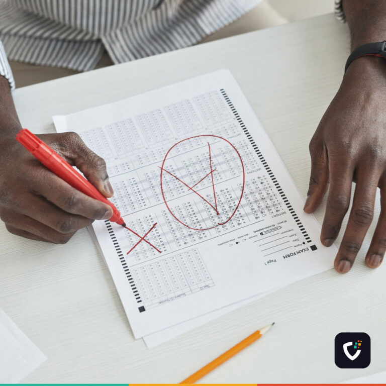 Hands marking a test paper in red pen, a tick circled and crosses beside the answers.